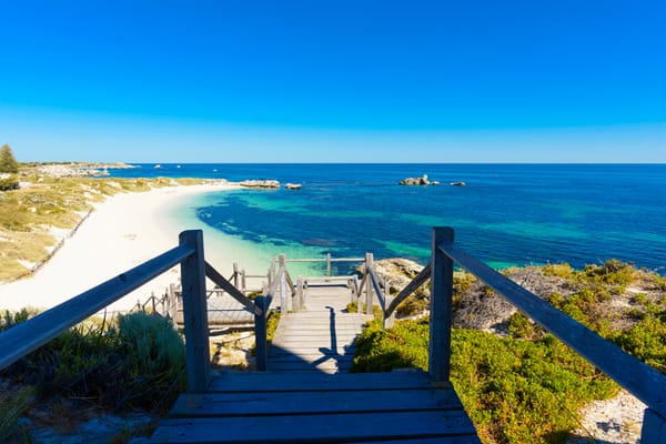 Looking out over a white beach and rocks appearing out of the water of bay on Rottnest Island, off the coast of Perth.