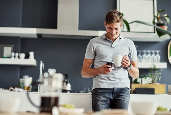 attractive young man reading his phone in the kitchen